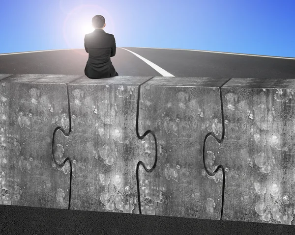 Business man sitting on four huge concrete puzzles connected tog — Zdjęcie stockowe