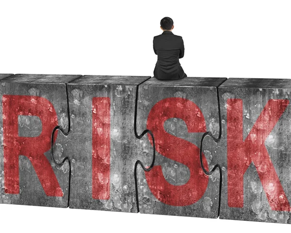 Man sitting on huge concrete puzzles with red risk word — Stok fotoğraf