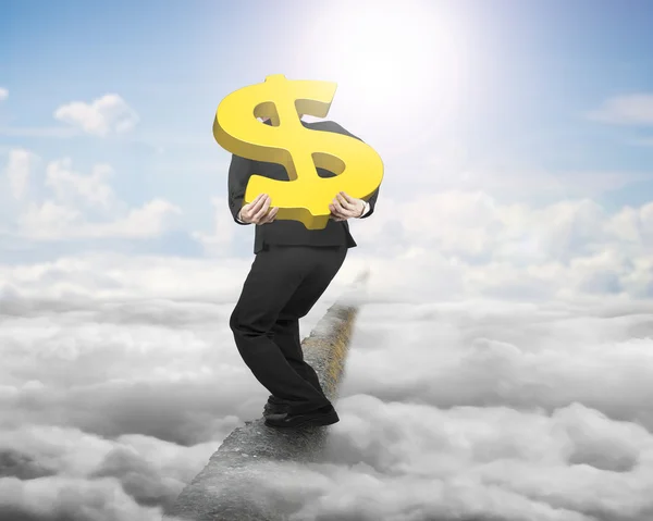 Businessman carrying gold dollar sign balancing on ridge with sk — Stock Photo, Image