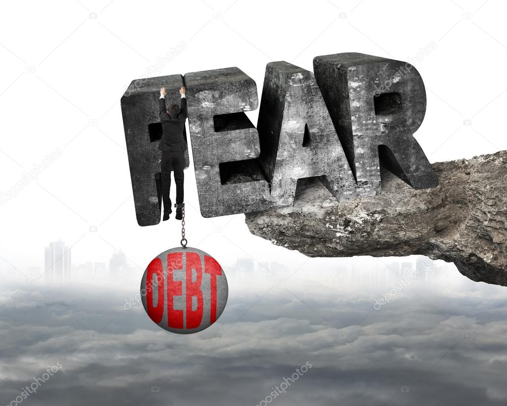 Man shackled debt ball hanging fear word edge cliff cloudscape