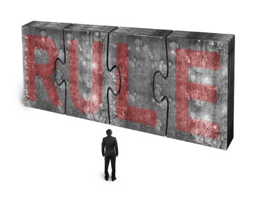 Man facing red rule word on huge concrete puzzles connected