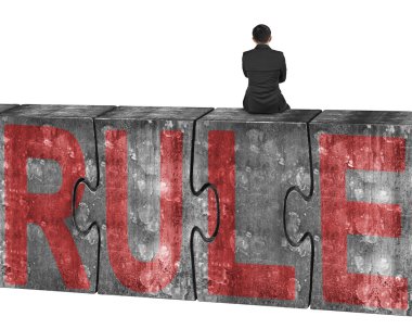 Man sitting on huge concrete puzzles with red rule word