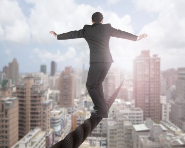 Businessman balancing on a wire with sky clouds cityscape clipart