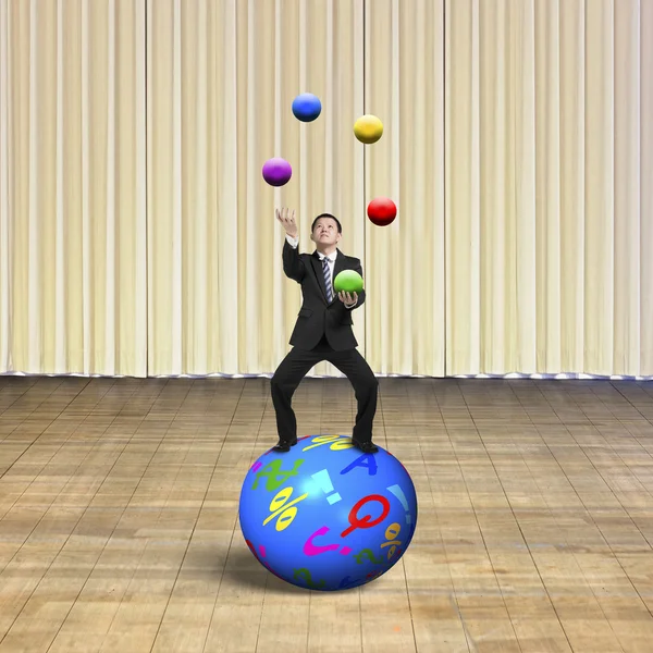 Homme d'affaires équilibrage sur la sphère jongler avec des boules — Photo