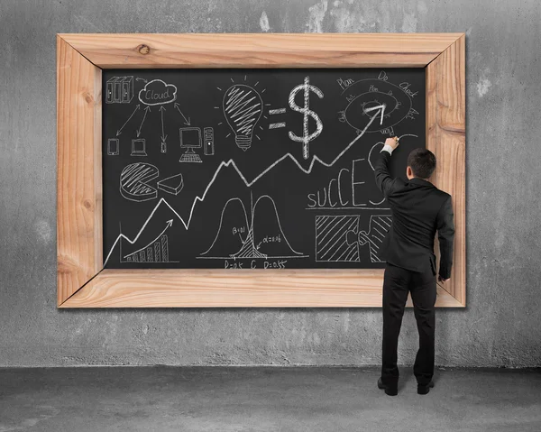 Businessman drawing business concept doodles on black chalkboard — Stockfoto