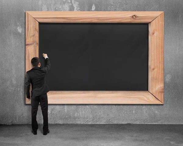 Businessman drawing on blank black chalkboard — ストック写真