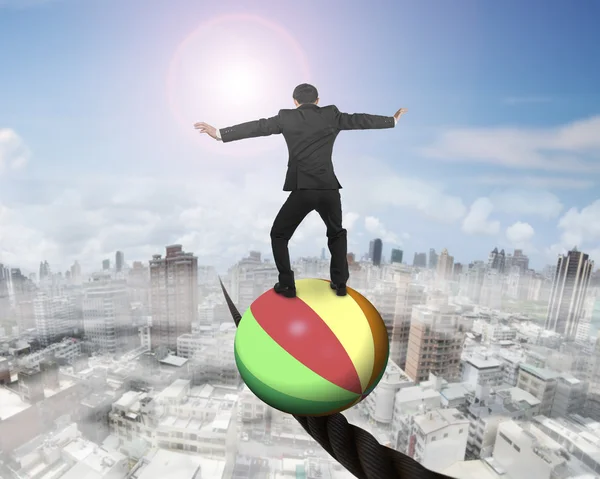 Businessman standing on ball balancing on wire — 图库照片