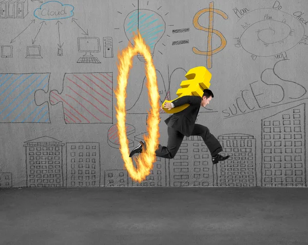 Businessman carrying golden euro sign jumping through fire hoop — Stock Photo, Image