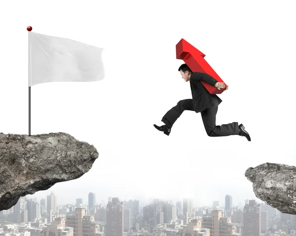 Jumping businessman carrying arrow up sign to flag on cliff — Stock Photo, Image