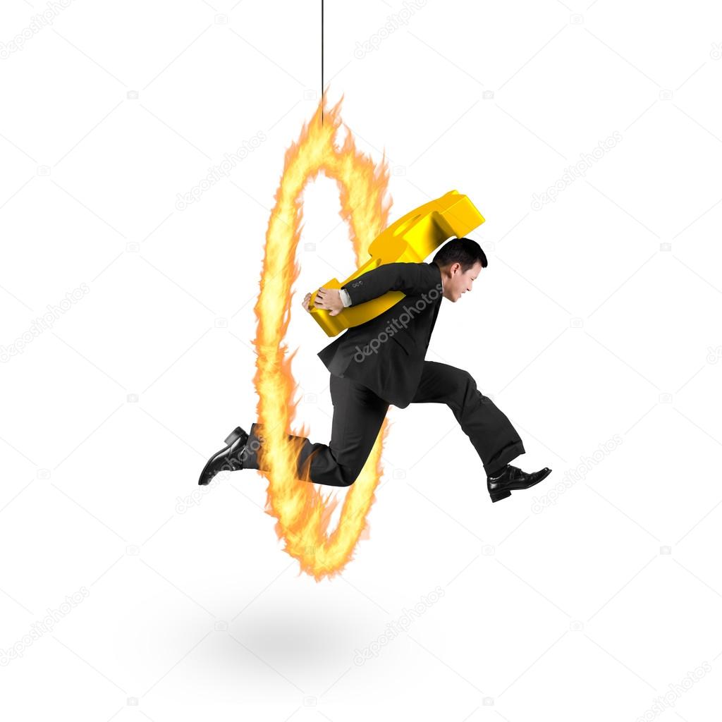 Businessman carrying golden dollar sign jumping through fire hoo