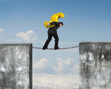 Businessman carrying golden dollar sign balancing on rusty chain