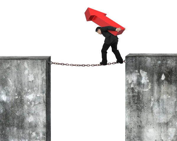 Businessman carrying red arrow sign balancing on rusty chain — Stock Photo, Image