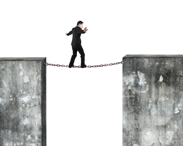 Businessman balancing rusty chain connected concrete walls — Zdjęcie stockowe