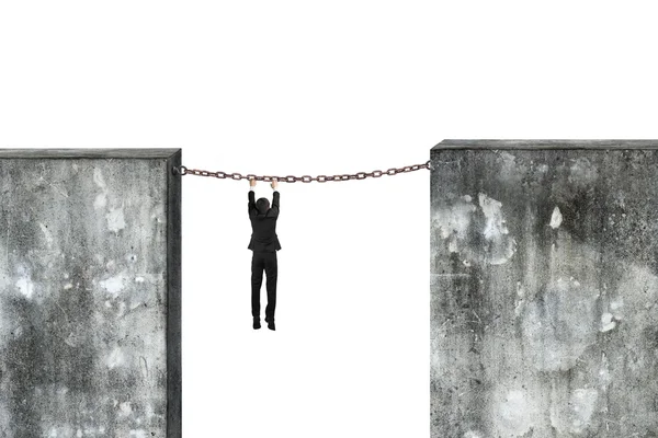 Businessman hanging rusty chain connected concrete walls — Stock Photo, Image