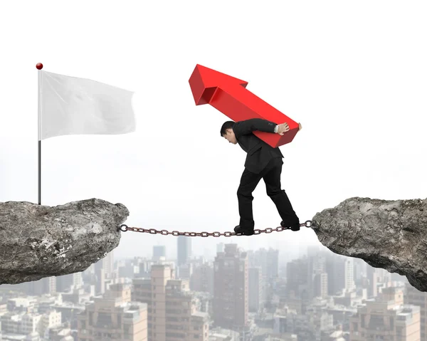 Businessman carrying red arrow sign balancing chain to white fla — Stockfoto