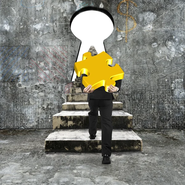 Man carrying golden jigsaw puzzle climbing concrete stairs towar — Stock Photo, Image