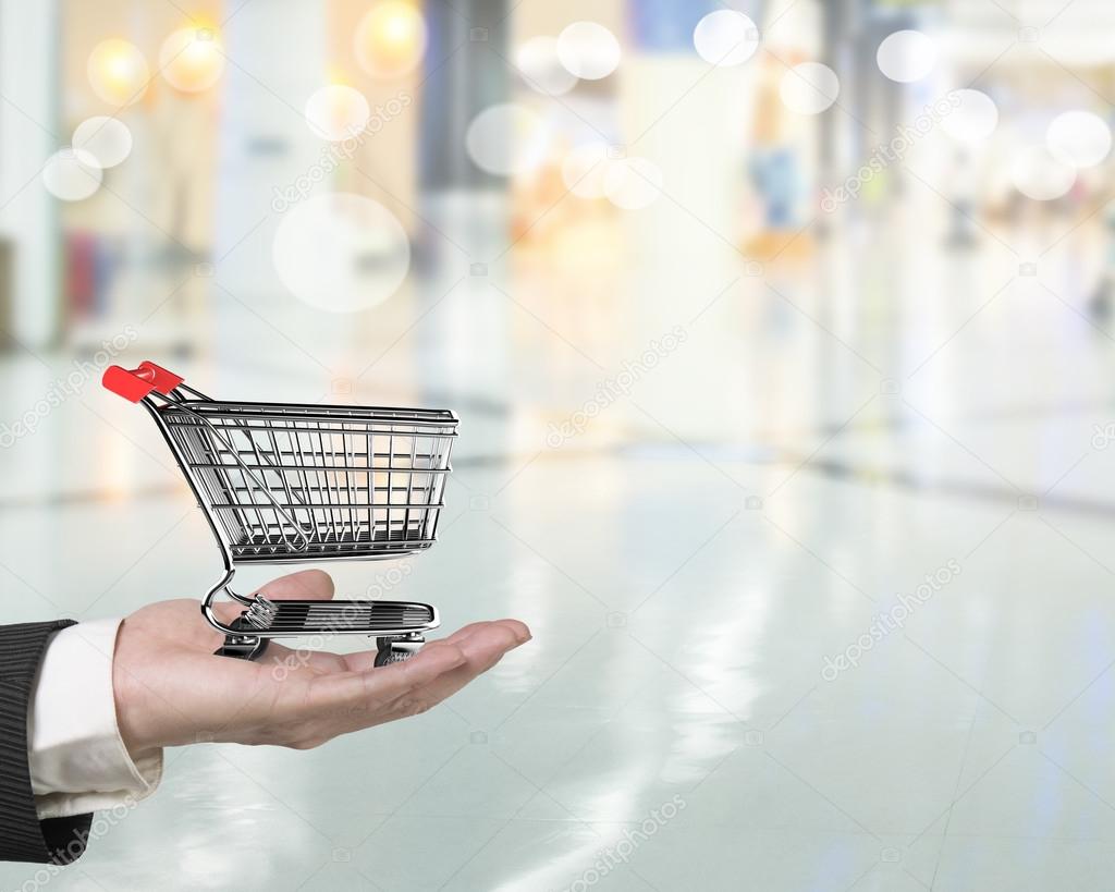 Hand holding small 3D empty shopping cart