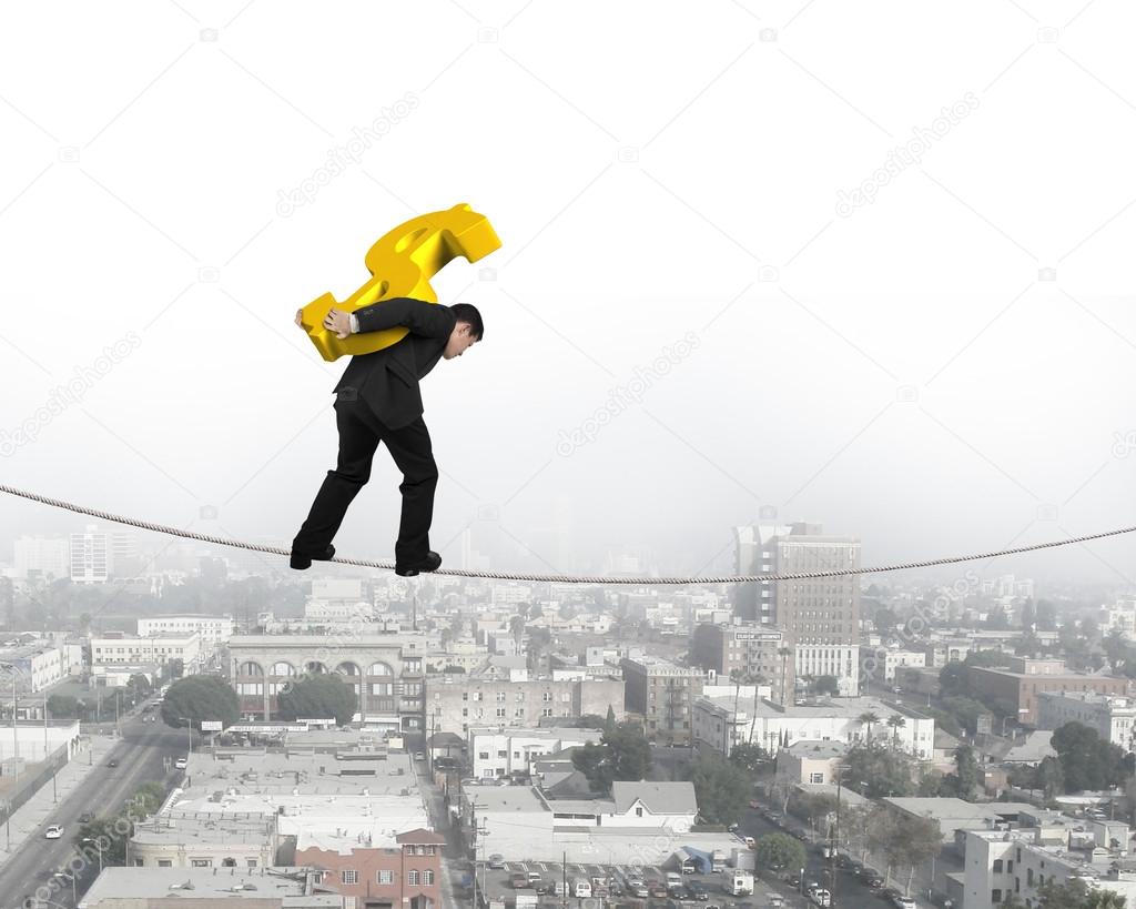 Businessman carrying golden dollar sign balancing on tightrope