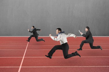 Three businessmen running on red track