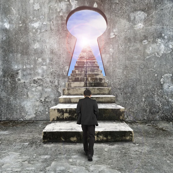 Man climbing old concrete stairs toward keyhole — Stock Photo, Image