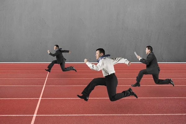 Three businessmen running on red track — Stock Fotó