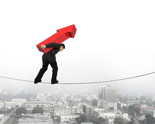 Empresário carregando sinal de seta vermelha balanceamento na corda bamba — Fotografia de Stock