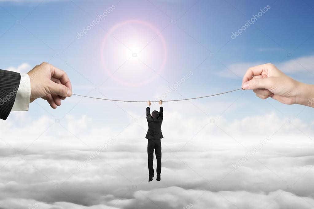 Businessman hanging on tightrope with man and woman hands holdin