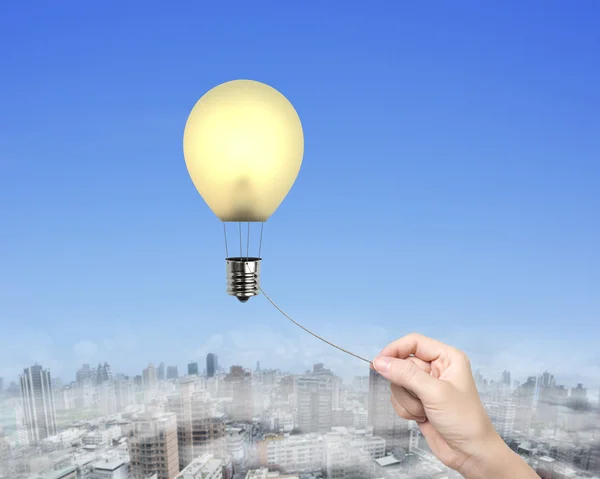 Woman hand pulling rope connected lightbulb hot air balloon — Stock Photo, Image