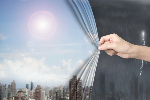 Mujer mano tirando del cielo soleado paisajes urbanos cortina que cubre tormentoso — Foto de Stock