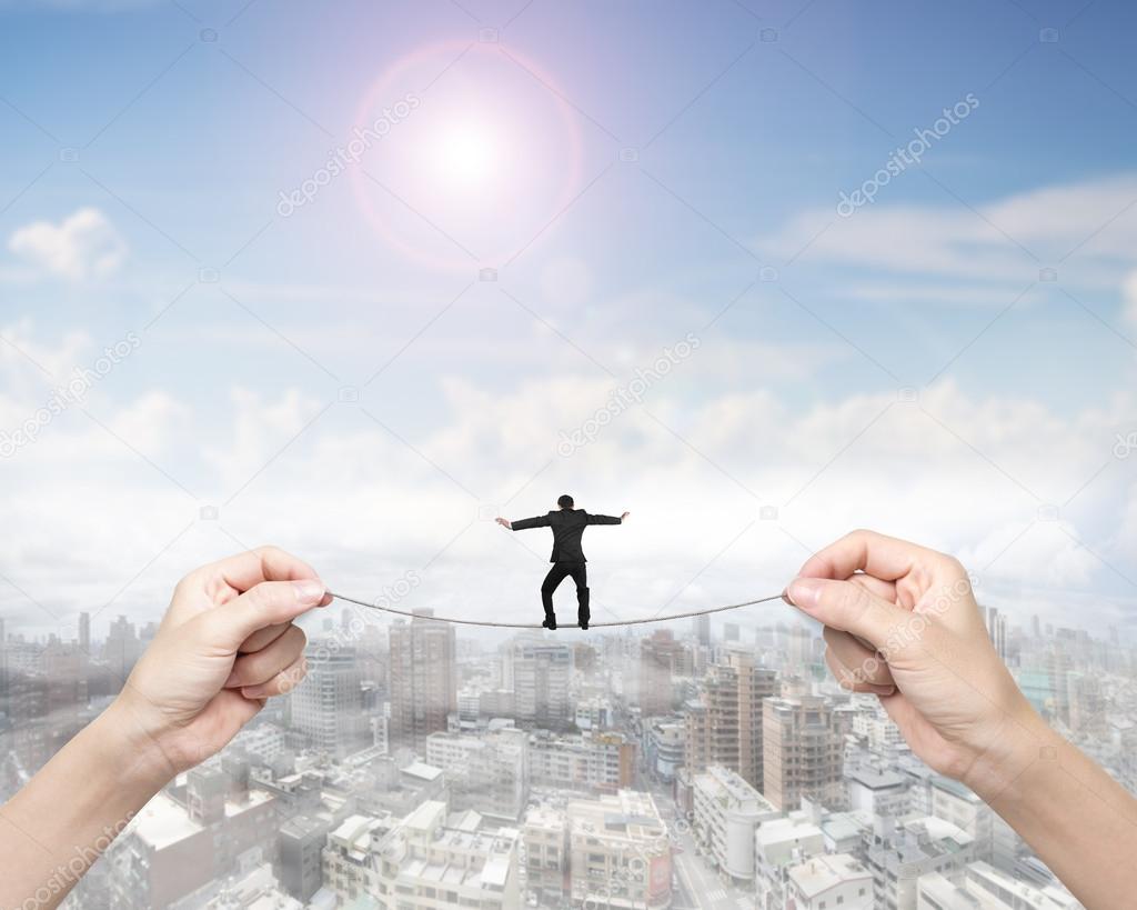 Businessman balancing on tightrope with woman two hands holding