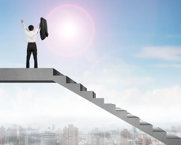 Businessman cheering on top of concrete stairs with city view — Stock Photo, Image