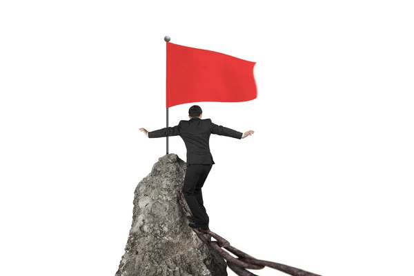 Businessman walking on rusty chain for red flag mountain top — Stock Photo, Image