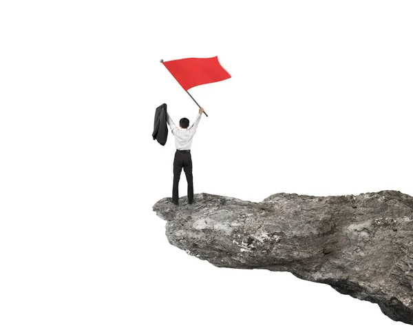 Businessman cheering and waving red flag on top of cliff — Stock Photo, Image