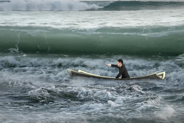 Empresario apuntando sentado en barco de dinero en el océano con olas — Foto de Stock