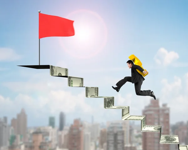 Hombre llevando oro USD a bandera roja en escaleras de dinero — Foto de Stock