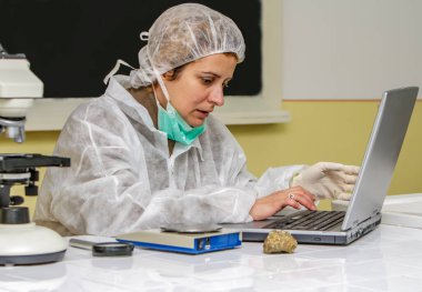 Female geogelist researcher analysing a rock at her workplace. clipart