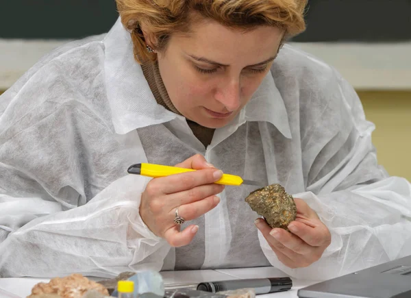 Female geologist researcher analysing a rock at her workplace.