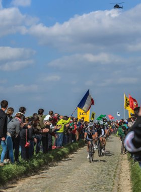 Carrefour de l'Arbre,France-April 13,2014: A group of cyclists (John Degenkolb-Giant Shimano,Fabian Cancellara-Trek,Zdenek Stybar-Omega Pharma- Quick Step) riding on the famous cobblestone sector Carrefour de l'Arbre in  Camphin-en-Pvle town 
