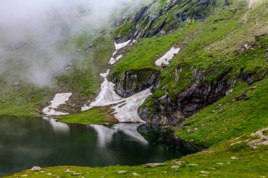 Romanya 'nın Fagaras Dağları' ndaki dağlık bir göl ve yüksek irtifadaki bulutların ayrıntıları. Konum: Balea Gölü.