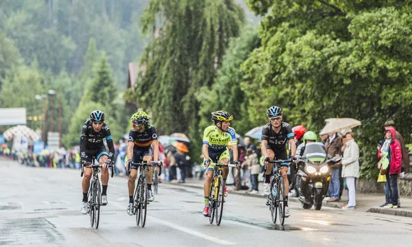 Quatro ciclistas andando na chuva — Fotografia de Stock