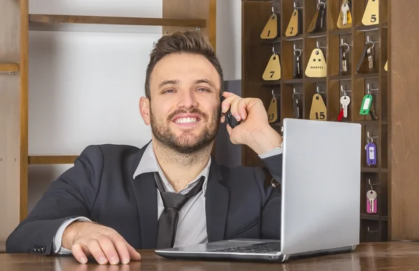 Uśmiechnięty recepcjonista rozmawia przez telefon — Zdjęcie stockowe