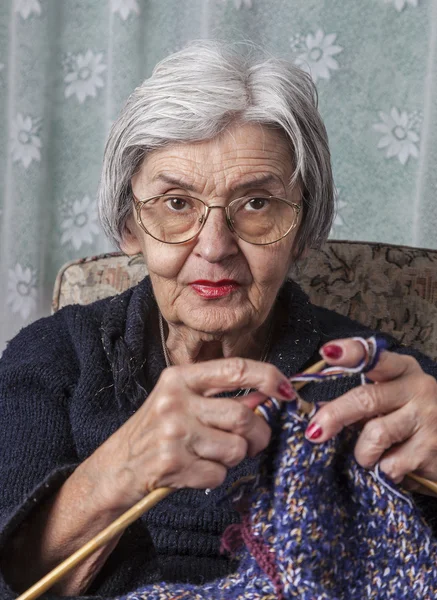 Velha mulher enrugada tricô em sua casa — Fotografia de Stock