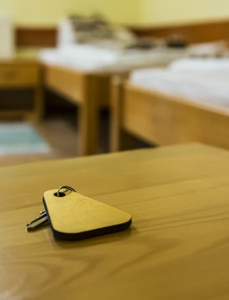 Uma chave de um quarto de hotel está em uma mesa de madeira — Fotografia de Stock