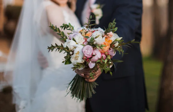 Wedding bouquet in hands of the bride and groom — Stock Photo, Image