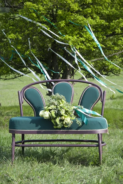 Turquoise Bank met een boeket tegen een boom — Stockfoto