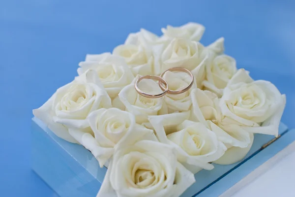 Весільні золоті кільця з білими трояндами в подарунковій коробці — стокове фото