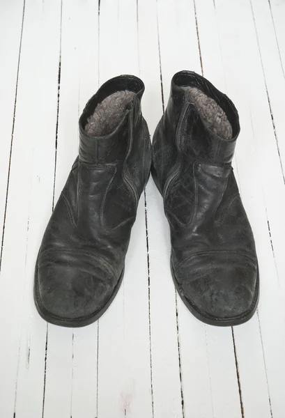 Παλιά μπότα πάνω από το λευκό ξύλινο πάτωμα — Φωτογραφία Αρχείου