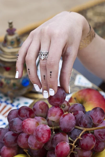 Ung kvinna håller färska druvor nära salver med äpple, päron — Stockfoto