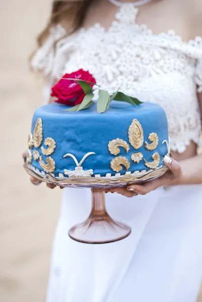 Pastel de boda azul en las manos de la novia y el novio, y rosas rojas en la parte superior —  Fotos de Stock