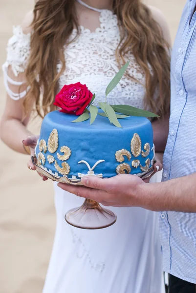 在新娘和新郎和顶上的红玫瑰手中的蓝色婚礼蛋糕。 — 图库照片